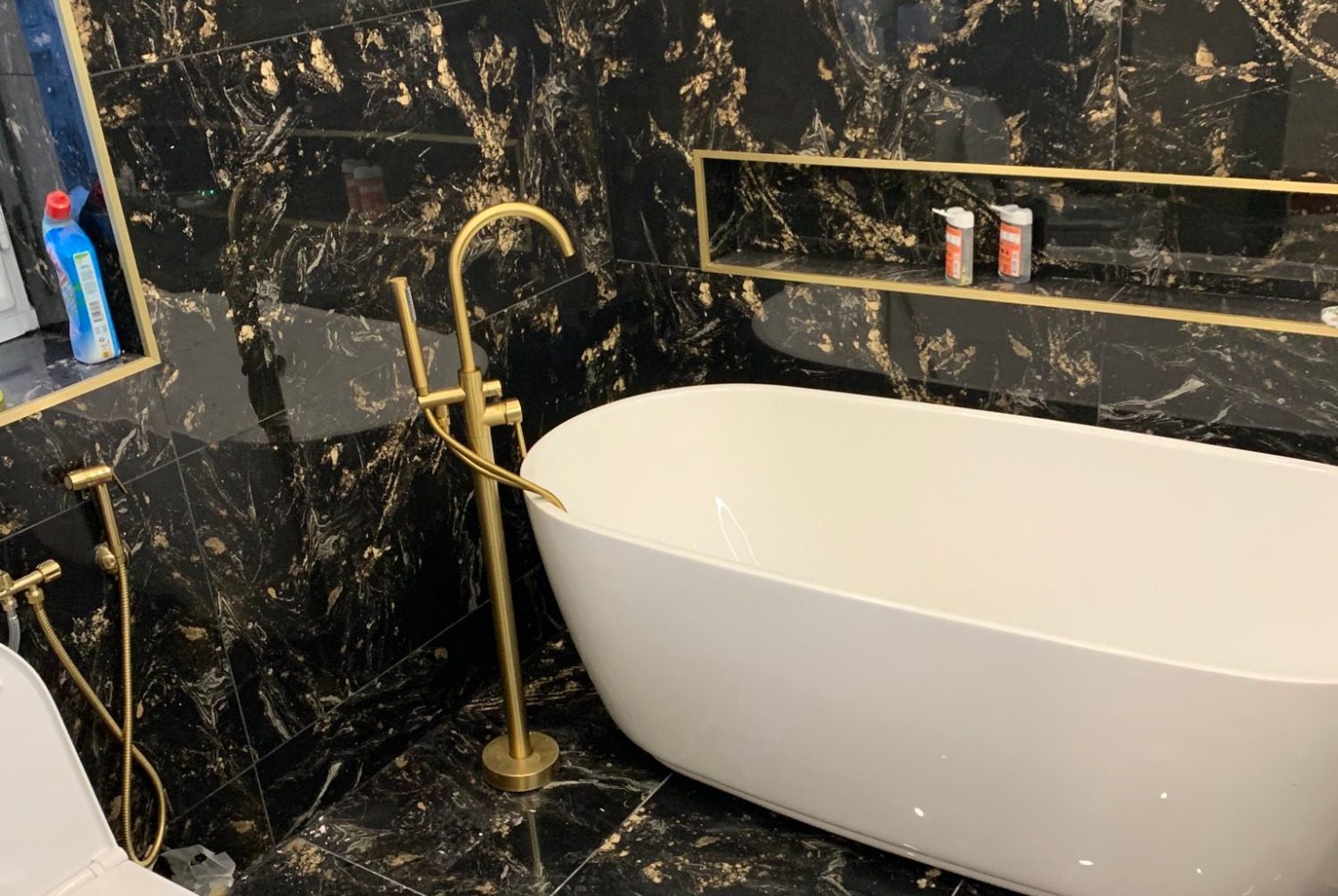 Baignoire blanche élégante sur fond de marbre noir avec robinet doré